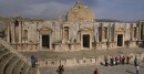 South Theater Stage * Built during the reign of Emperor Domitian, between 90-92 AD, the South Theater seats more than 3000 spectators and serves today as the primary venue for the Jerash Festival of Culture and Arts. The first level of the ornate stage, originally 2-stories has been reconstructed and is still used today. The remarkable acoustics allows a speaker at the center of the orchestra floor to be heard by the entire auditorium without raising his/her voice.Two vaulted passages lead into the orchestra, and four passages at the back of the theater give access to the upper rows of seats. Some seats could be reserved and the Greek letters which designate them can still be seen.     * 648 x 336 * (82KB)